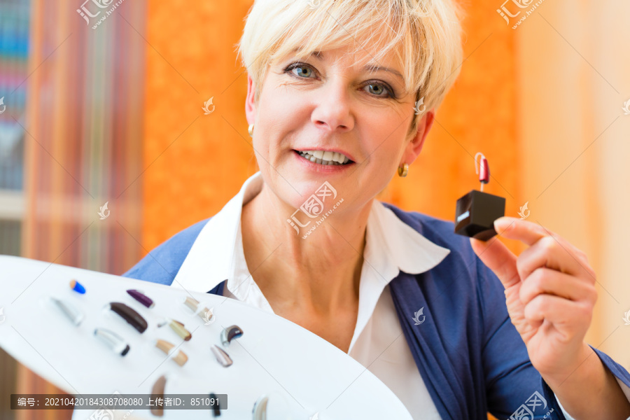 老年妇女或有听力问题的女性退休人员做听力测试，可能需要助听器，她正在挑选他们