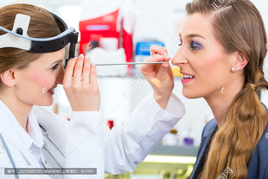 医生-年轻的女性顾问或耳鼻喉科专家-与患者一起在她的诊所，用抹刀检查喉咙