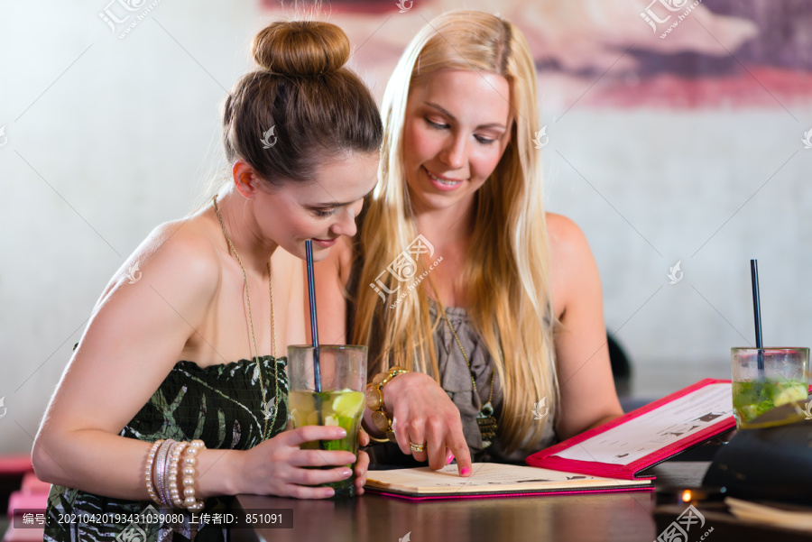 年轻女性或同事下班后坐在咖啡馆、酒吧或餐厅，选择菜单