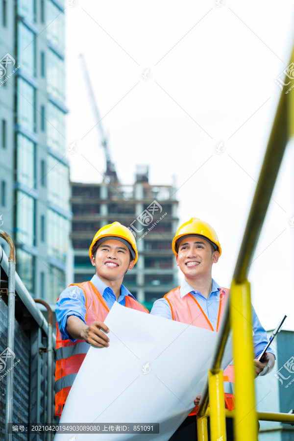 亚裔印尼建筑工人在建筑工地上绘制蓝图或平面图