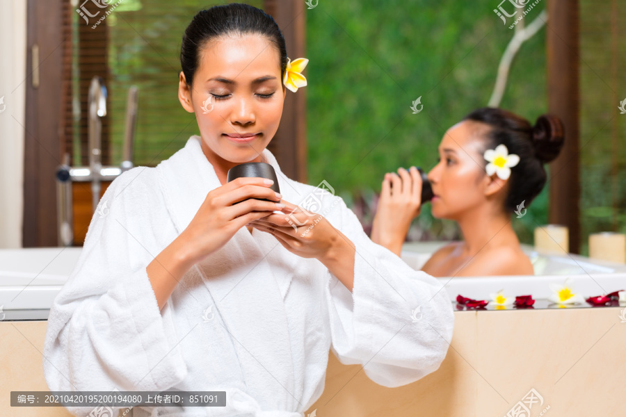 印尼亚裔妇女在健康美容日水疗中心享受芳香疗法浴和喝凉茶排毒