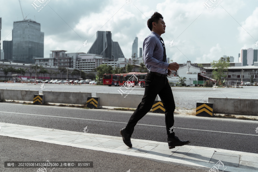 一个商人在路上逃跑的全长肖像。健康的商人在城市的轨道上运行。