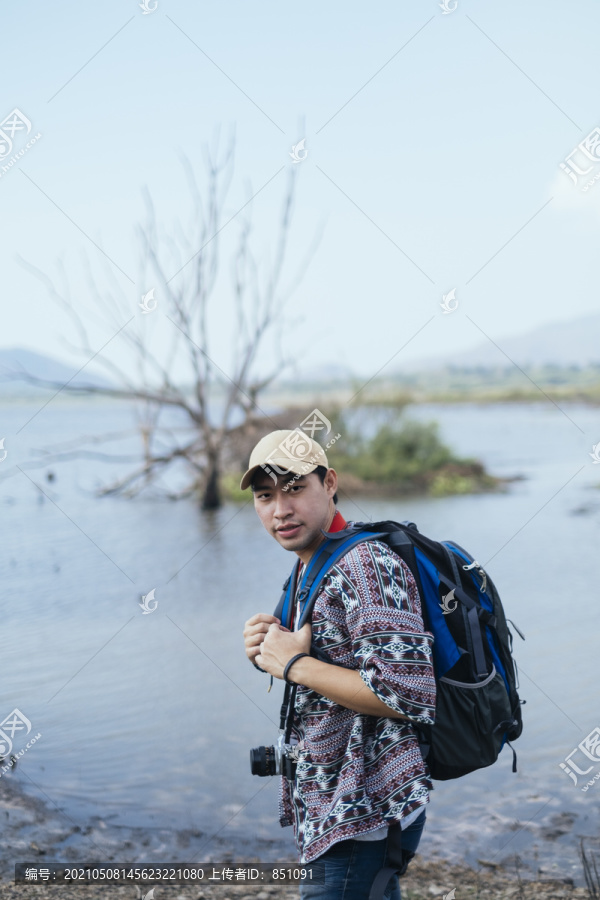 雄鸟站在沼泽地，森林里有一棵枯树。