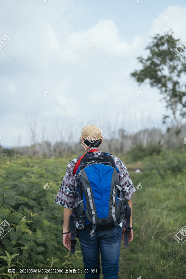 行走在有树、湖、山的自然小径上的男性冒险家。