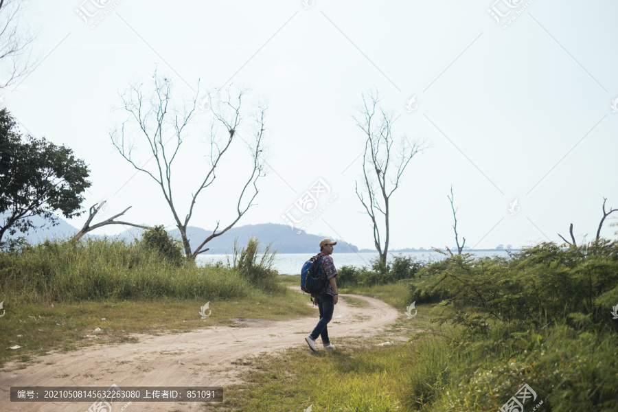 男性冒险家喜欢在阳光明媚的日子里走在自然小径上，用相机拍下大自然的照片。