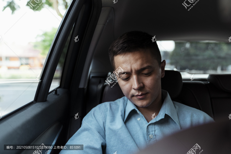 在汽车后座穿着蓝色衬衫的商人皱眉。