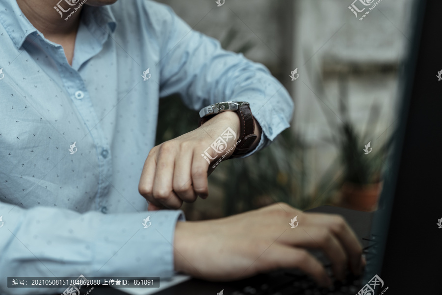 自由职业者在看手表，因为他的工作时间不多了，他必须再工作一段时间。