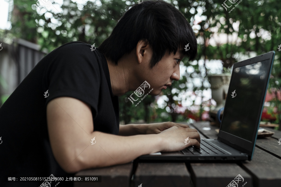 一个穿黑色t恤衫的人在电脑里仔细地看他的工作。