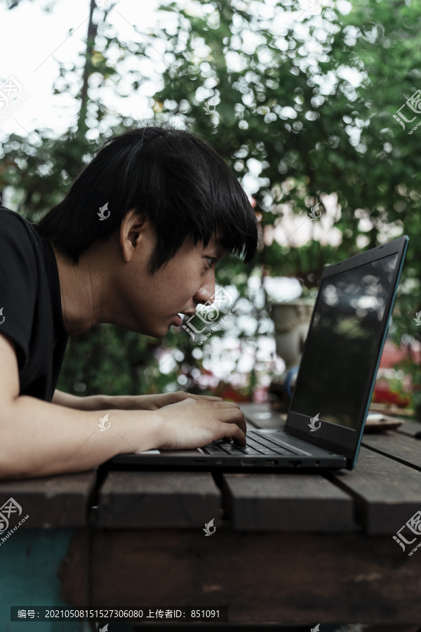 一个穿黑色t恤衫的男人重新检查智能手机和电脑之间的信息。