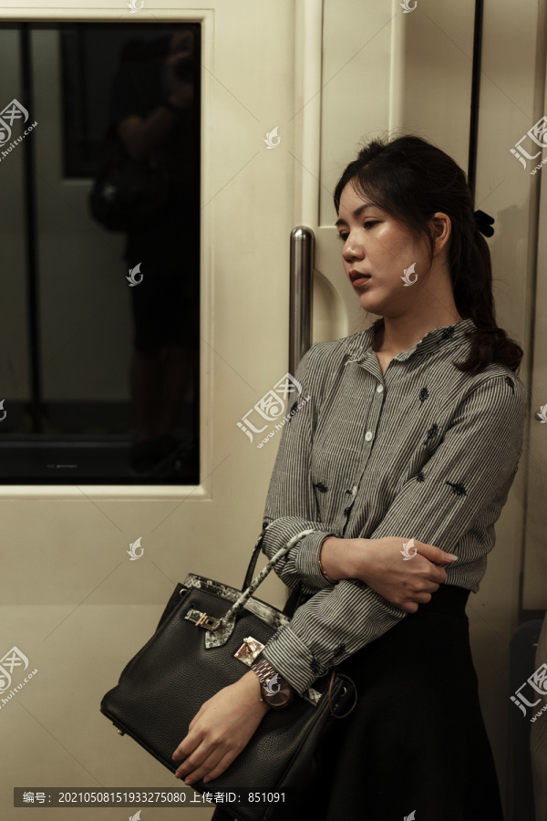 悲伤的亚泰女人晚上站在火车里。工作累了。