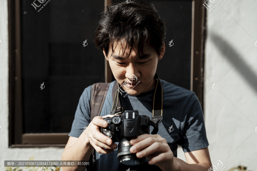 一位年轻的亚洲摄影师正在用相机拍照。