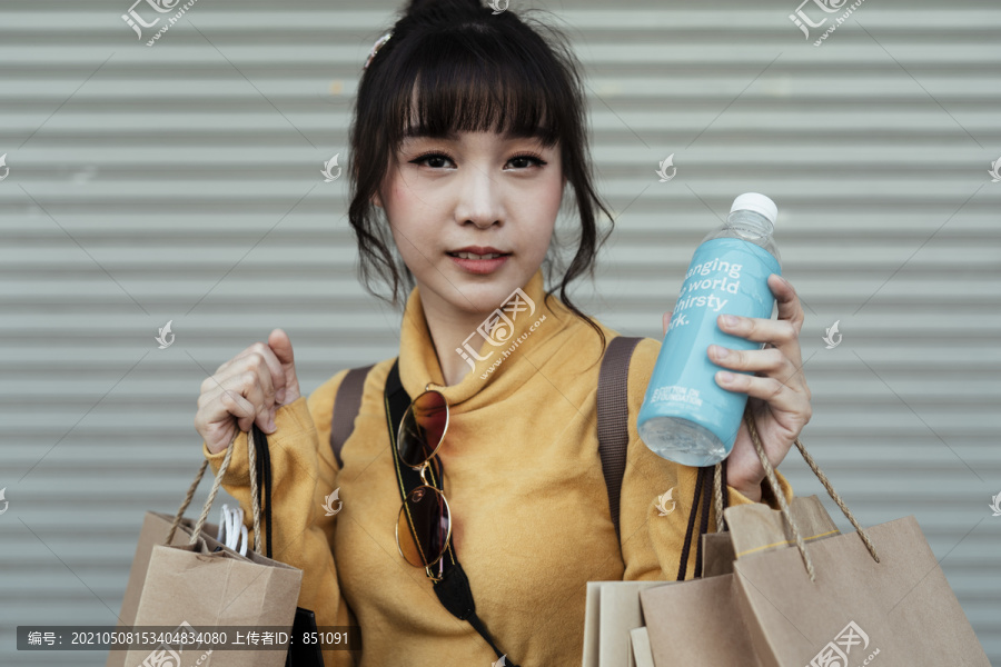 美丽可爱的亚洲女人拿着水塑料瓶和购物塑料袋。生态购物。