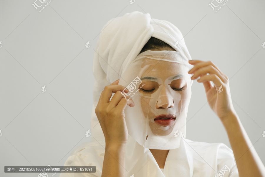 穿着白色浴袍的年轻女子摘下脸上的化妆面具。