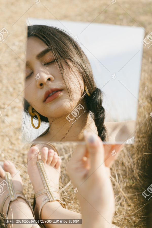 白衣黑辫女子戴着耳环倒映在方镜下，站在干燥的草原上，做着白日梦。