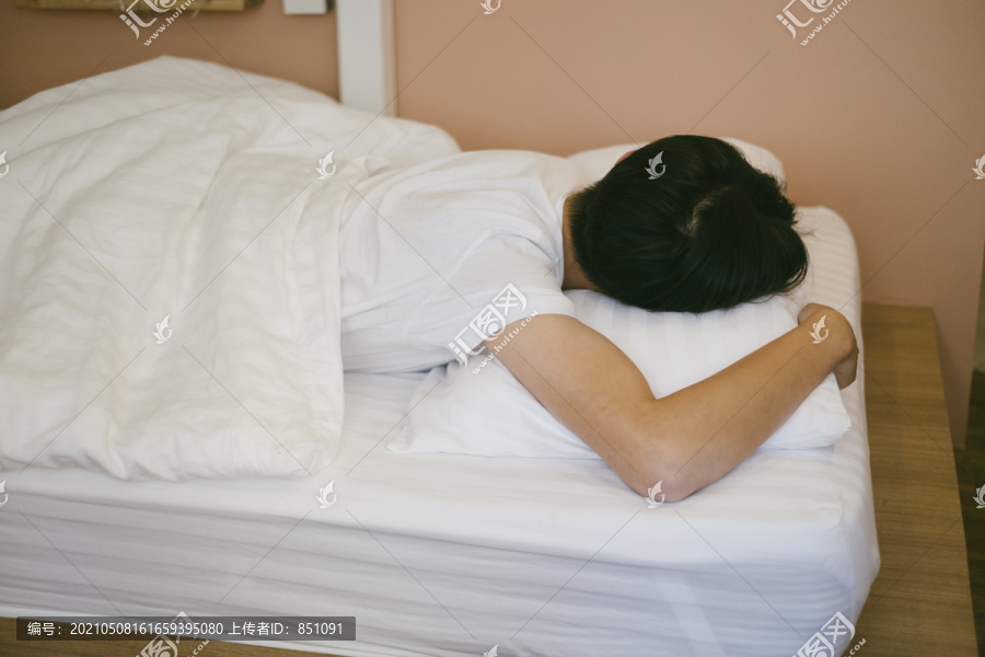 黑发小子趴在床上，抱着枕头睡觉。
