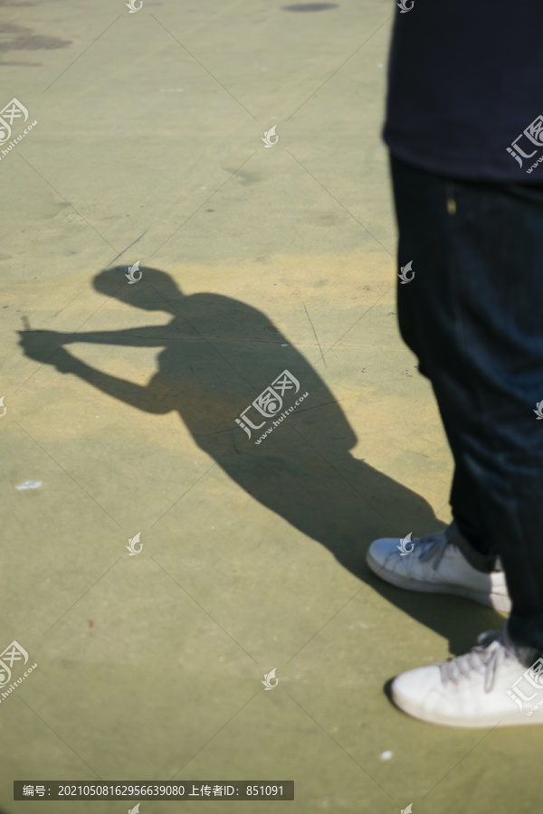 一个男人站在阳光下享受影子时的腿的剪短图像。