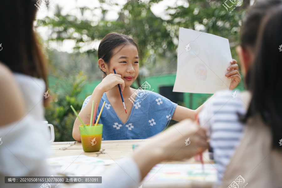 快乐的亚洲妹妹在纸上画水彩。很自豪地展示她的作品。创造力和想象力。