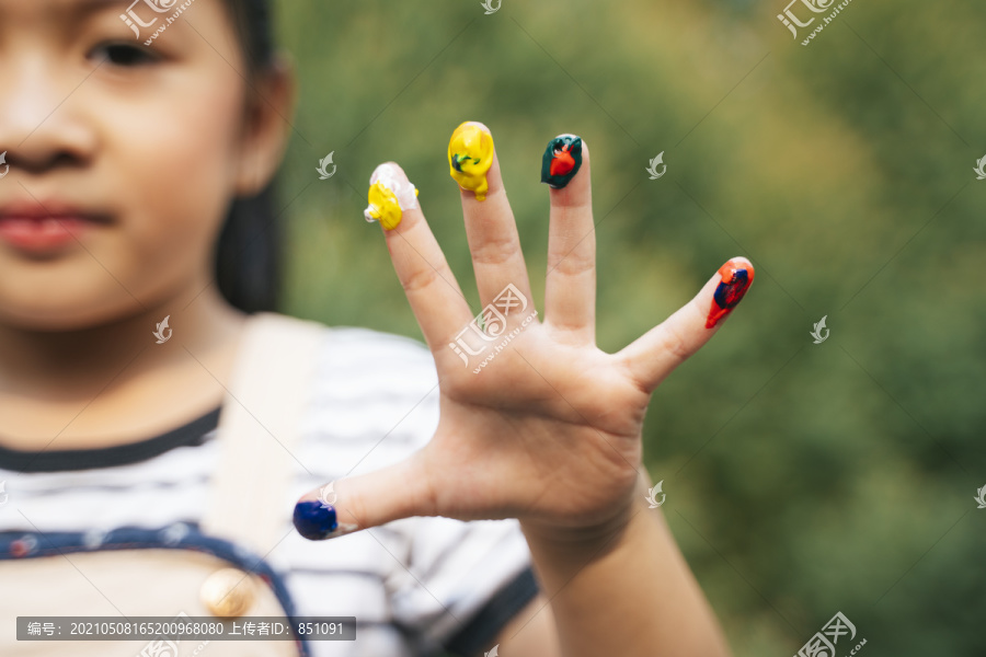 有趣的小女孩，手上涂着彩色颜料。用彩画把小女孩的手拉近。