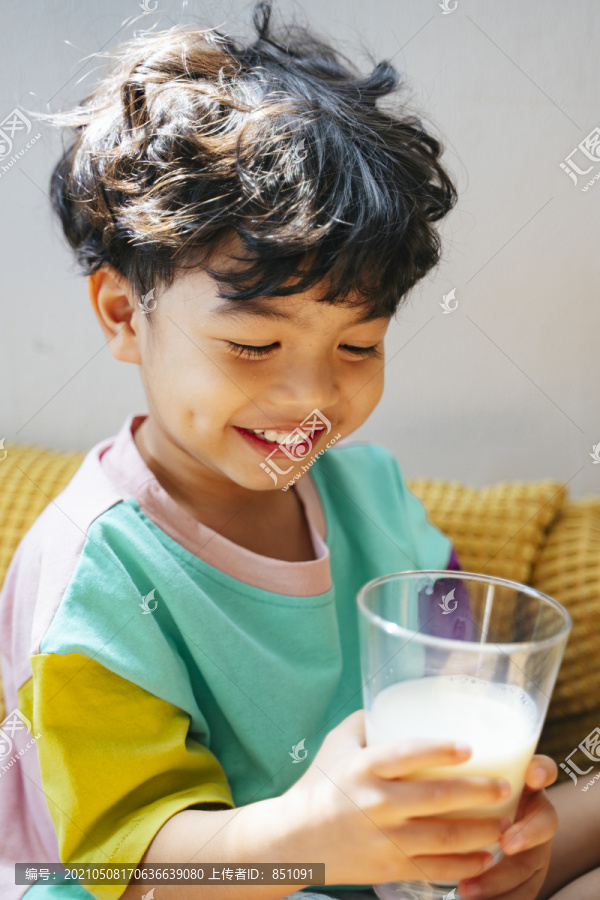 小男孩快乐地喝着透明玻璃杯里的牛奶。