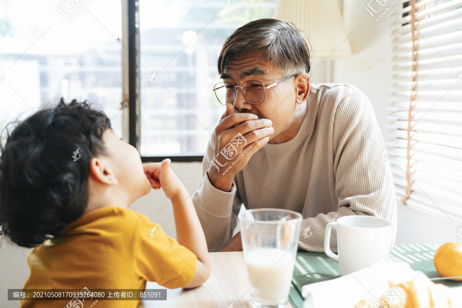 孙子在早餐时告诉爷爷他的牙齿。
