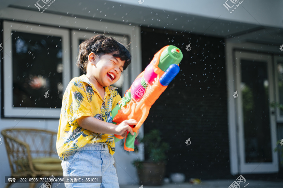 泰国一年一度的传统节日“泼水节”，一个小男孩在他家里用水枪和橡皮管泼水。