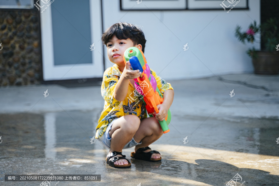 泰国一年一度的传统节日“泼水节”，一个小男孩在他家里用水枪和橡皮管泼水。