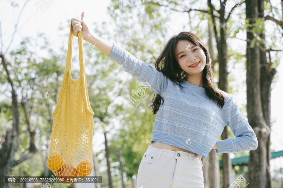 穿着蓝色t恤的可爱女孩微笑着把网袋拉起。