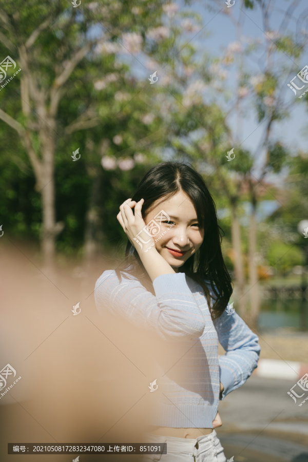 可爱的女孩站在阳光下微笑着拍照。