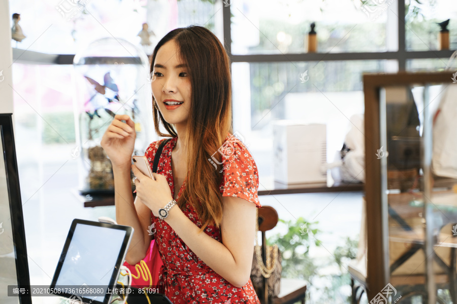 一位身穿红色连衣裙的亚洲年轻女子在柜台店点面包和小甜饼。