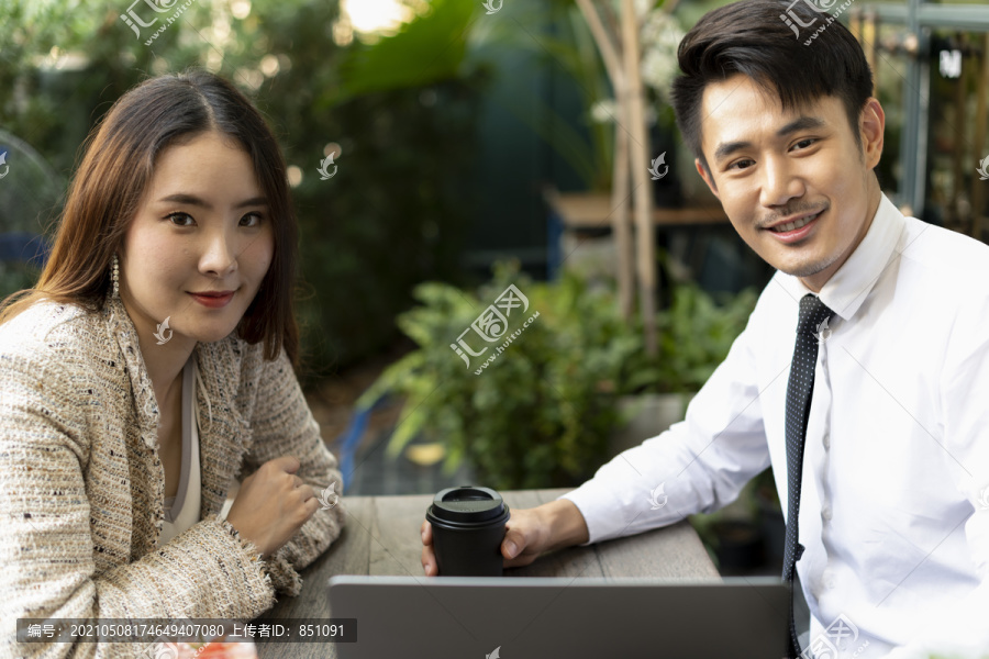 两个亚洲商人一起在咖啡店工作，看着笔记本电脑。