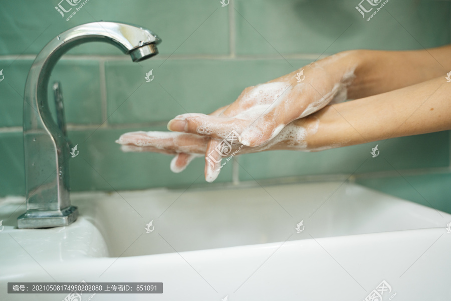 卫生观念。用肥皂洗手的水龙头下有水的绿色卫生间卫生间。在流水下用肥皂洗手。