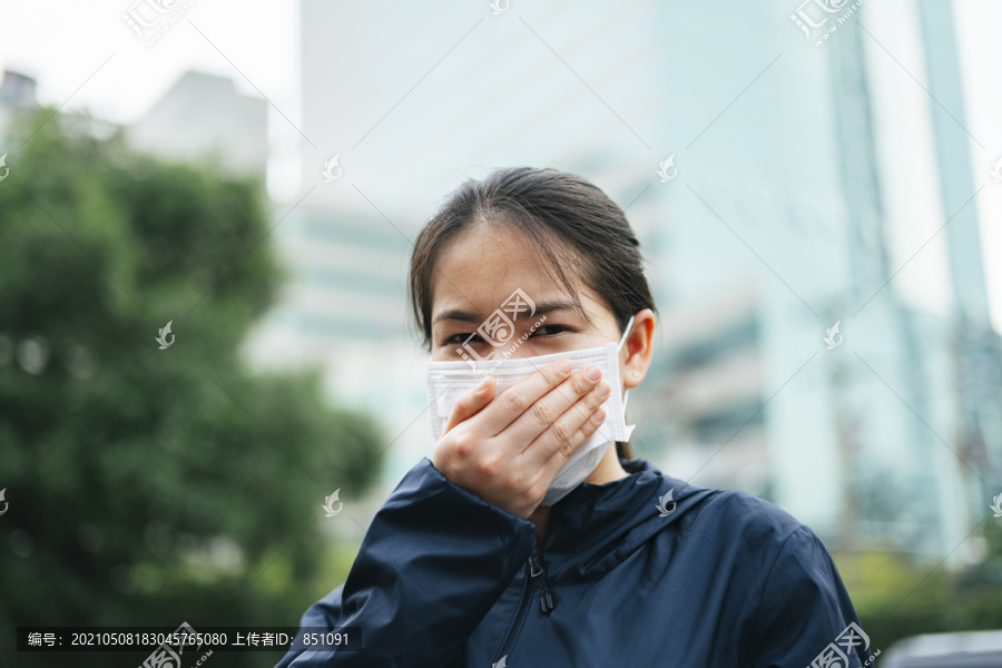 戴着口罩的亚洲妇女在城市里行走时不能呼吸。