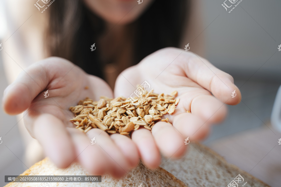妇女手上放着许多谷物的剪短图像，放在餐桌上，放着一杯咖啡和面包。