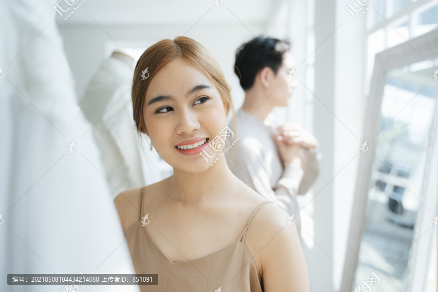 新人参观婚纱摄影棚挑选自己的婚纱，一位女士看婚纱。