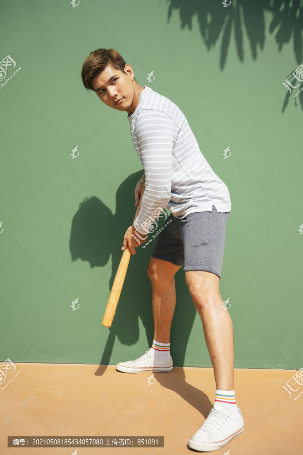 英俊的亚洲男子拿着棒球棒。准备击球姿势。拿着棒球棒的棒球运动员。