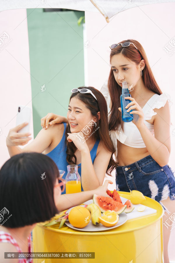 夏日派对上，女人们用智能手机自拍。一群人喜欢聚会。