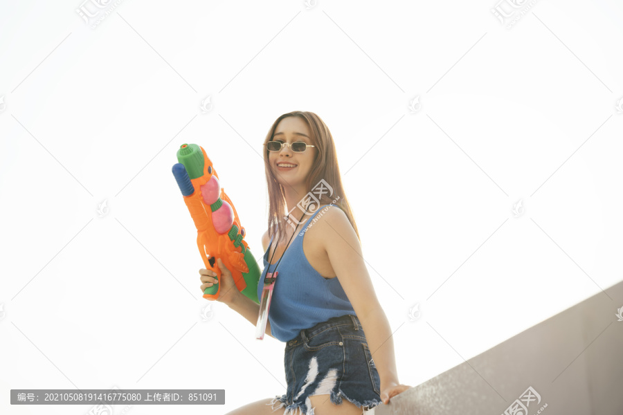 性感女人穿蓝色背心衬衫和水枪。泰国曼谷的泼水节。