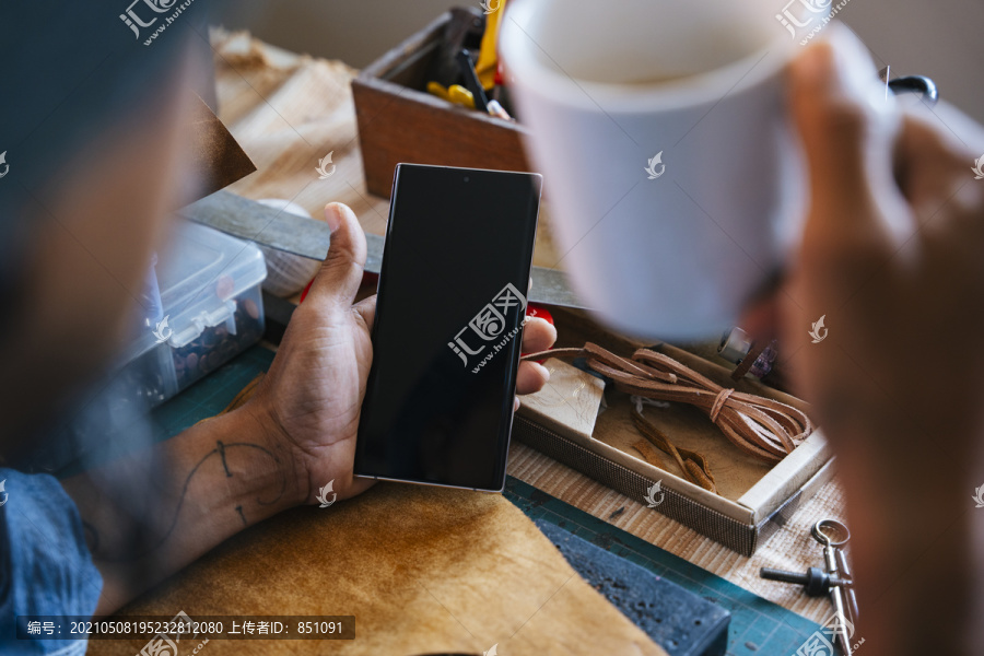 一个男人在休息时间喝咖啡的时候，手里拿着一个不规则的智能手机。