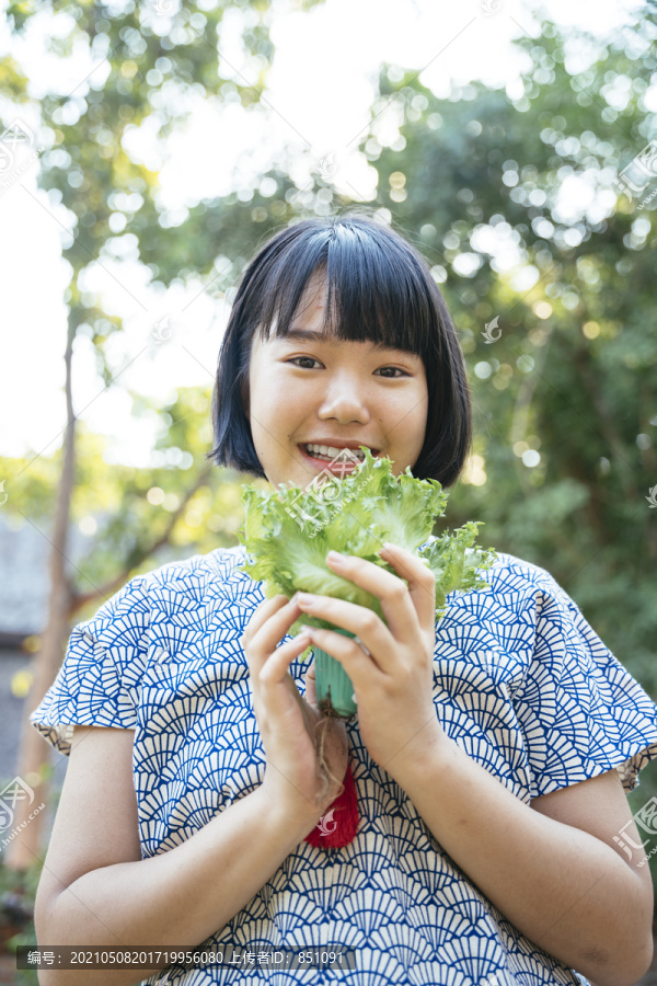 生态旅游-美丽的亚泰女子鲍勃发型手拿绿色新鲜蔬菜。蔬菜爱好者。健康食品。