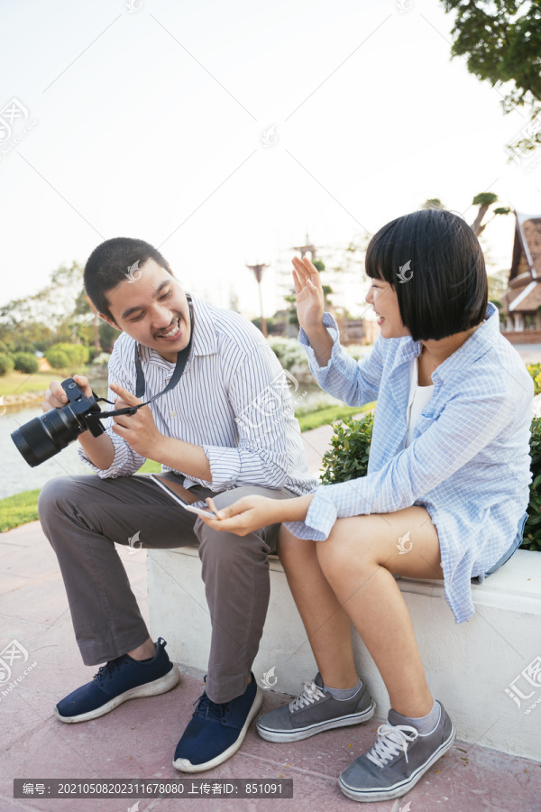 一对亚洲可爱的夫妇在镜头前看他们的照片。旅行者夫妇。