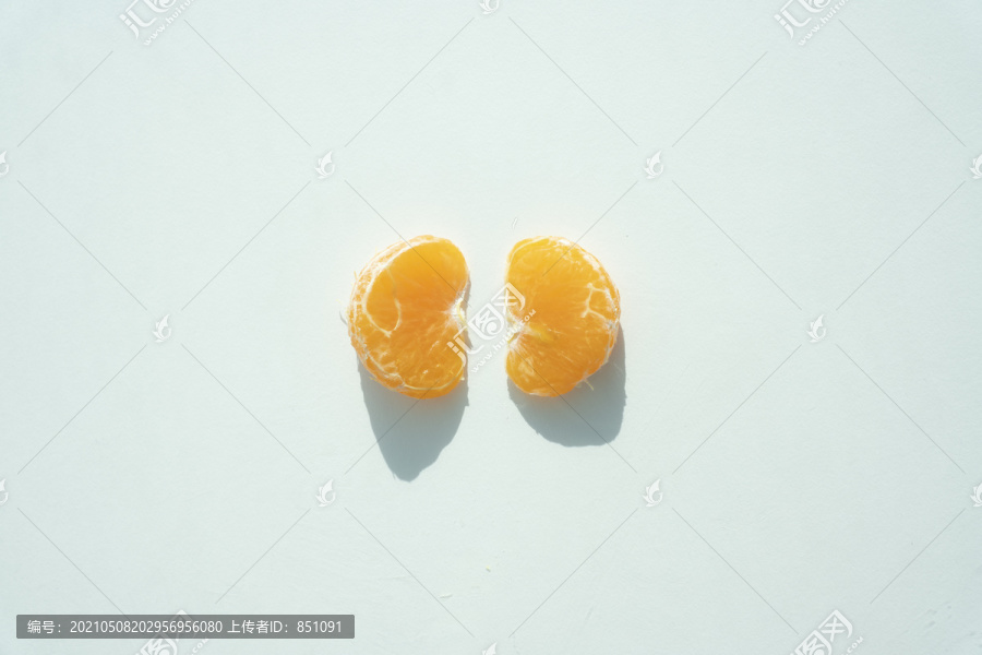 两片去皮的橘子，白色的背景像一个肾脏。