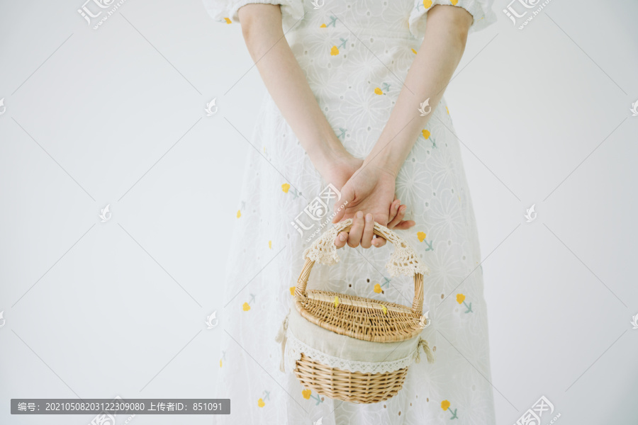 在白色背景下，穿着白色衣服的美女手持野餐篮的剪影。