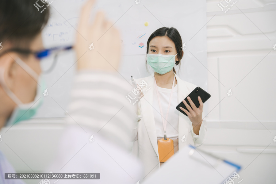 亚泰护士在医院会议室向医生做报告。使用互联网在智能手机上阅读脚本。