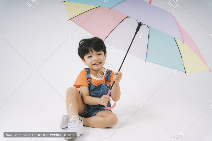 小男孩得到彩色粉彩雨伞时很高兴，他很喜欢雨伞。