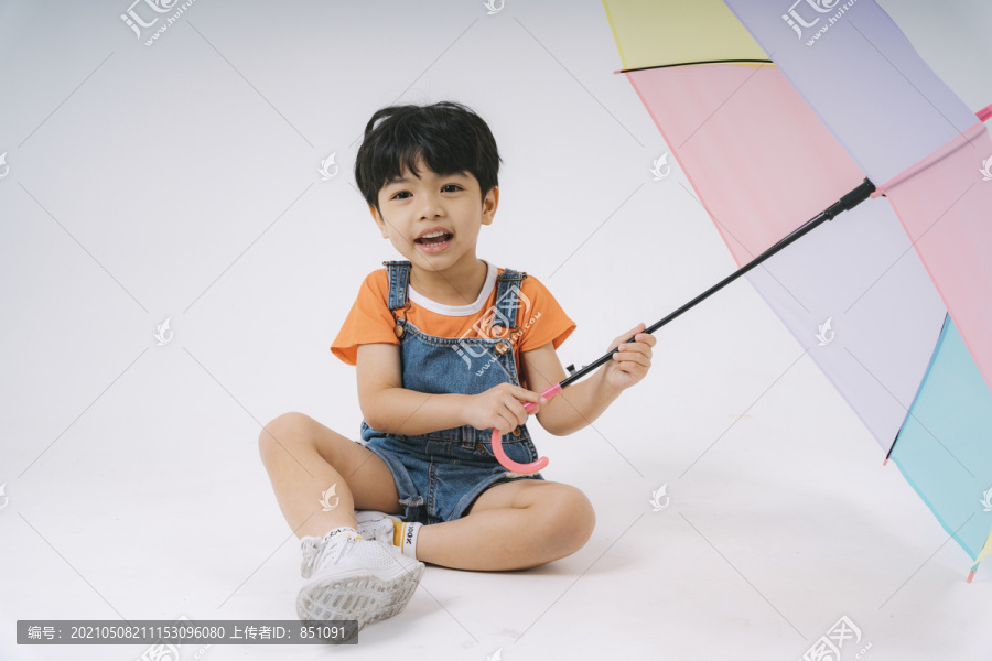 小男孩得到彩色粉彩雨伞时很高兴，他很喜欢雨伞。