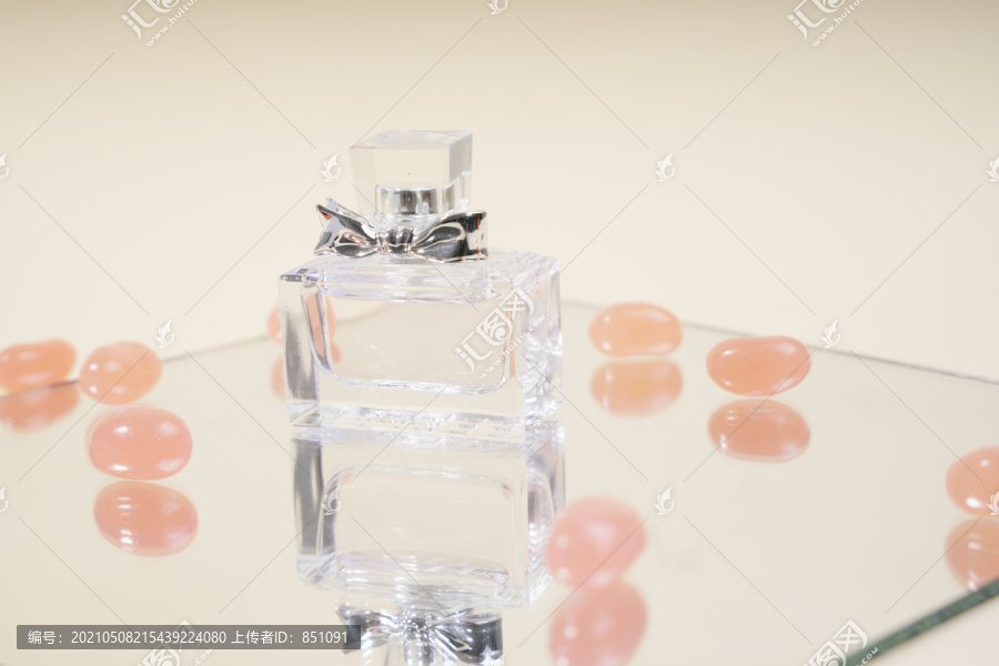 镜板上的香水玻璃瓶，白色背景上有糖果环绕。