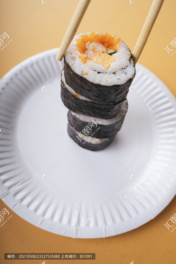 Maki在纸盘子和筷子上把寿司卷在一起。吃寿司。