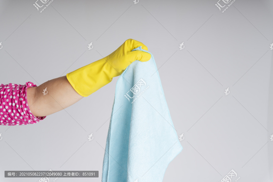 清洁工手戴黄色防护手套，手拿蓝色抹布隔离白色背景。Covid-19冠状病毒预防。