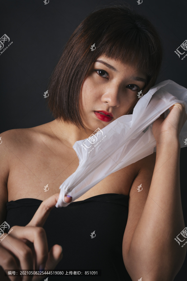 塑料时尚概念。美丽的亚泰妇女短发塑料袋隔离黑色背景。