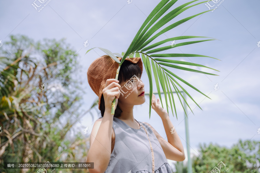 年轻的泰国亚裔女子在郊外与大绿叶合影旅行。本地旅行。